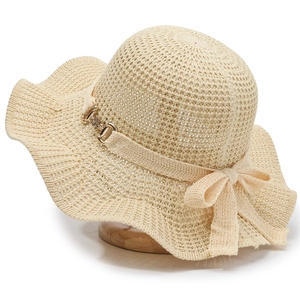 Women's knit sun hat with wide wavy brim and elegant bow tie decoration in light beige