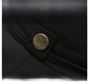 Detail of a vintage bronze metal buckle with engraved text on black twill fabric hat