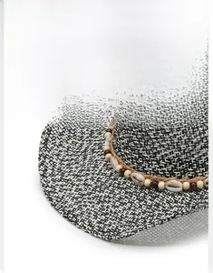 Detail of woven sun hat with black and white texture and decorative shell beaded band