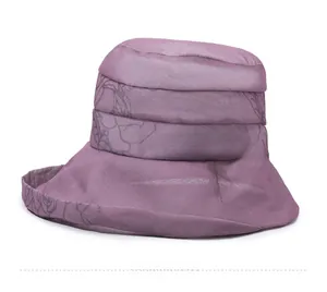 Detail view of purple wide brim sun hat with floral print and gold leaf pendant accessory