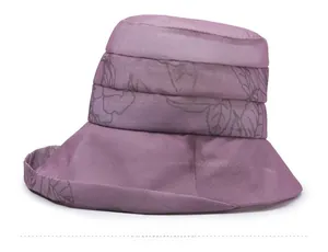 Detail of purple sun hat with leaf print and a small gold leaf metal charm attachment