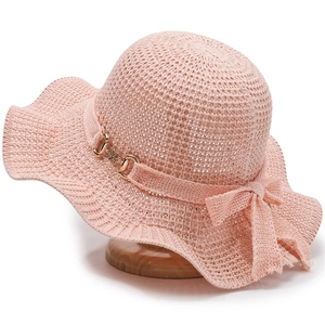 Pink knitted sun hat with wide wavy brim and decorative bow for summer beach vacation