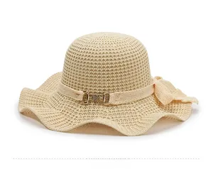 Detail of knitted sun hat with wide wavy brim, ribbon trim and golden metal buckle