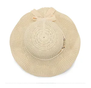 Top down view of beige knitted sun hat with wide wavy brim and delicate bow detail