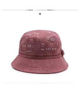 Dettaglio ravvicinato del cappello a secchiello rosso scuro con motivo a griglia bianca