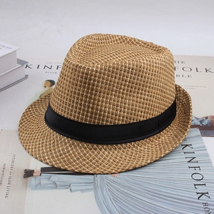 Détail d'un chapeau fedora rétro en paille tressée posé sur des magazines de mode