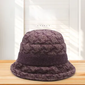 Detailed top view of a dark purple textured cloche hat with a stylish bow on wooden surface