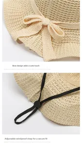 Detail of beige straw sun hat featuring a decorative bow and adjustable windproof strap