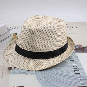 Gros plan d'un chapeau Fedora en paille avec ruban noir sur des magazines Kinfolk