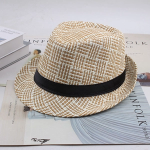 Détail d'un chapeau de paille tissé avec ruban noir posé sur un magazine tendance