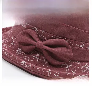 Détail d'un chapeau de soleil bordeaux avec texture tissu, imprimé floral et nœud décoratif