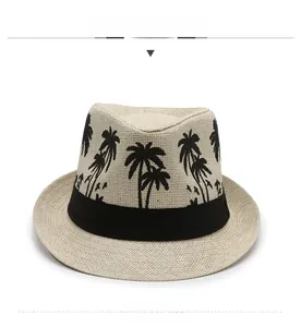 Detail of light beige straw fedora featuring black ribbon and coconut tree embroidery