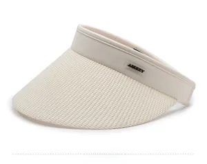 Detailed close-up of beige woven sun hat with black rubber brand tag on the brim