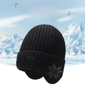 Dettaglio cappello a costine nero con paraorecchie e motivi a fiocchi di neve grigi