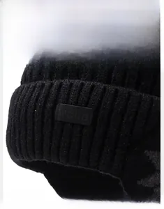 Dettaglio del berretto in maglia nera a coste con patch in pelle e fodera in pile