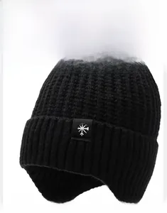 Close-up of black knitted beanie showing thick wool texture and snowflake patch detail