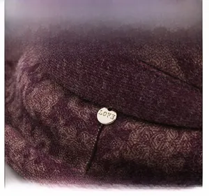 Detail of purple knitted wool hat with a gold metal button engraved with LOVE text
