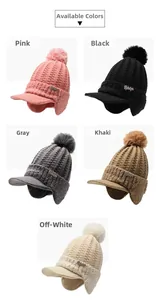 Detailed close-up of chunky knit ear-flap beanies with pom-poms in five assorted colors