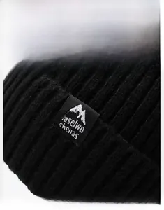 Close-up of black ribbed knit beanie with mountains logo patch and woven texture detail