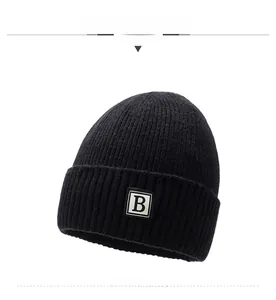 Detailed front view of black cable knit beanie featuring white square letter B patch