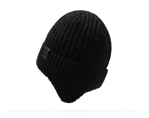 Detail of black knitted beanie featuring thick wool texture and a snowflake logo patch