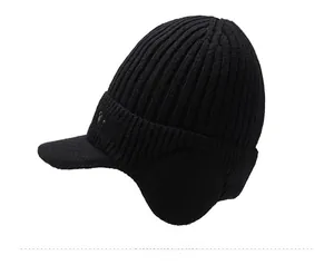 Detail of black winter knit hat with earflaps, visor, and sport embroidery texture