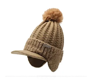 Detailed side view of a thick knit earflap hat with pompom and metal script logo