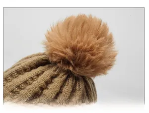 Detail of plush faux fur pom-pom on khaki chunky knit winter hat with warm texture