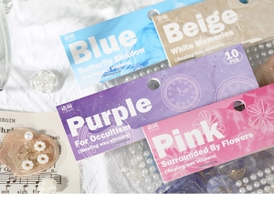 Close-up of sealing wax stickers with gold foil, pearls and sequins on fabric background