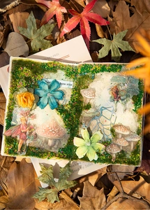 Nahaufnahme von Waldelfen-Scrapbooking-Papier mit Moos, Stoffblumen und Herbstlaub