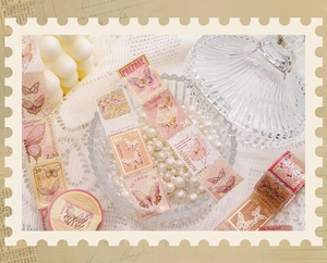 Detalle de cinta washi con sellos de mariposa vintage y pan de oro en elegante expositor