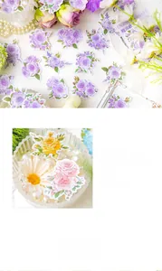 Macro detail of die-cut floral stickers featuring roses and daisies for DIY journaling