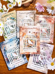 Detail of vintage bird and floral decorative paper with intricate laser-cut birdcage overlay