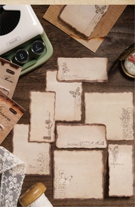 Detail of burnt-edge vintage stickers with butterflies and flowers on dark wood surface