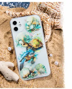 Detail of transparent iPhone case with sea turtle and shell patterns on beach sand