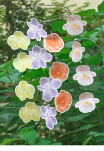 Detail of hanging floral wind chime with colorful petals and beads in nature