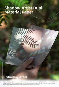Close-up of artistic light and shadow theme scrapbooking paper held against sunlight