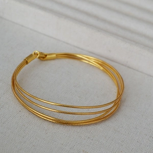 Detail of multi-layer snake bone chain bracelet in gold-plated brass minimalist style