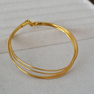 Detail of multi-layer gold snake bone chain bracelet with triple-strand metal texture