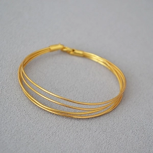 Minimalist multi-layer gold snake chain bracelet with textured metallic weaving design