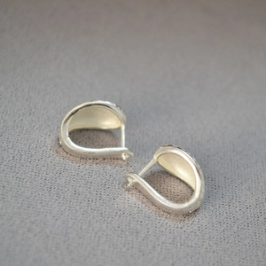 Minimalist matte silver U-shaped hoop earrings with a brushed texture on grey leather