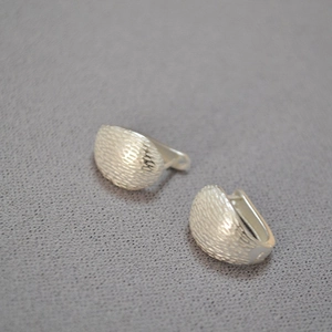 Close-up of matte silver earrings featuring a retro brushed texture and J-shaped design