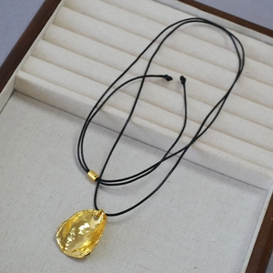 Collier minimaliste en laiton doré avec pendentif ondulé et cordon en cuir noir sur boîte