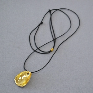 Détail du pendentif organique en laiton plaqué or sur un cordon noir ajustable