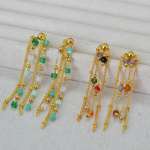 Detail of gold chain tassel earrings featuring multi-colored beads on a jewelry tray