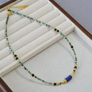 Collier fait main perles turquoise, lapis-lazuli et accents dorés sur plateau à bijoux