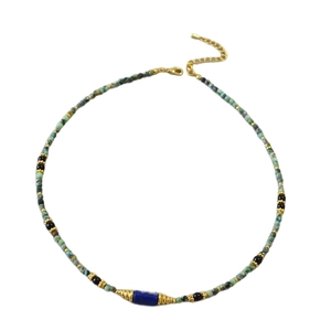 Collier artisanal en perles de turquoise et lapis-lazuli avec accents dorés sur fond blanc