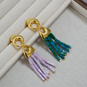 Macro detail of bohemian beaded tassel earrings featuring golden geometric metal studs