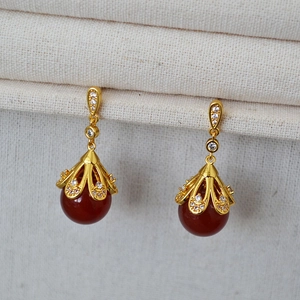 Detail of vintage gold plated brass earrings with red agate beads and sparkling zircon