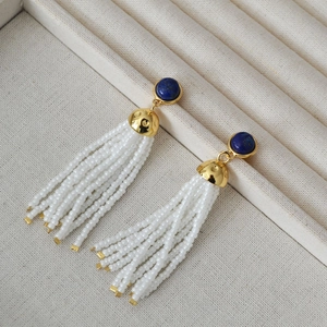 Lapis lazuli stud earrings with white seed bead tassels and gold-tone finish in a jewelry box